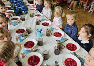 dzieci wspólnie siedzą przy świątecznym stole, spożywają potrawy