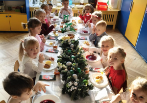 dzieci wspólnie siedzą przy świątecznym stole, spożywają potrawy