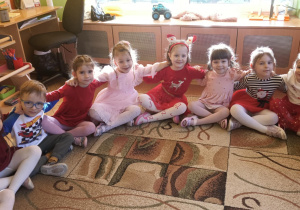 Dzieci siedzą na dywanie i wspólnie kolędują