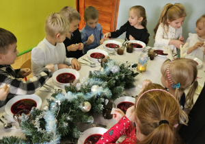 dzieci wspólnie siedzą przy świątecznym stole, spożywają potrawy