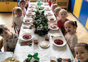 dzieci wspólnie siedzą przy świątecznym stole, spożywają potrawy