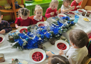 dzieci wspólnie siedzą przy świątecznym stole, spożywają potrawy