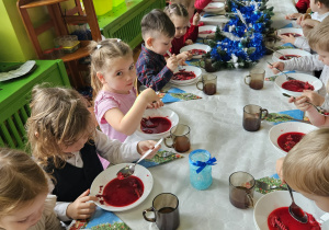 dzieci wspólnie siedzą przy świątecznym stole, spożywają potrawy