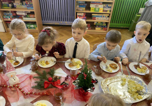 dzieci wspólnie siedzą przy świątecznym stole, spożywają potrawy