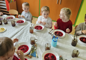 dzieci wspólnie siedzą przy świątecznym stole, spożywają potrawy