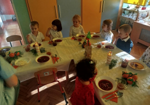 dzieci wspólnie siedzą przy świątecznym stole, spożywają potrawy
