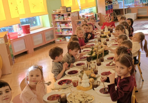 dzieci wspólnie siedzą przy świątecznym stole, spożywają potrawy