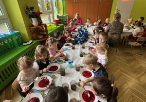 dzieci wspólnie siedzą przy świątecznym stole, spożywają potrawy