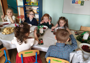 dzieci wspólnie siedzą przy świątecznym stole, spożywają potrawy