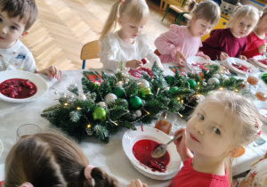 dzieci wspólnie siedzą przy świątecznym stole, spożywają potrawy