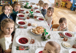 dzieci wspólnie siedzą przy świątecznym stole, spożywają potrawy