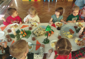 dzieci wspólnie siedzą przy świątecznym stole, spożywają potrawy
