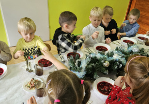 dzieci wspólnie siedzą przy świątecznym stole, spożywają potrawy