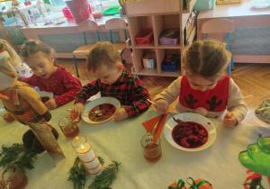 dzieci wspólnie siedzą przy świątecznym stole, spożywają potrawy