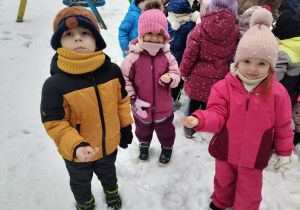 Dzieci trzymają na dłoniach ziarno dla ptaków.