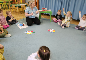 Dzieci siedzą w kole i zadają pytania.