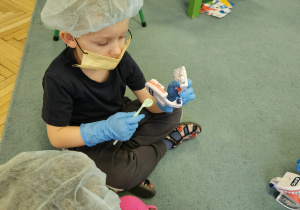 Dzieci w maseczkach, rękawiczkach szczotkują zęby