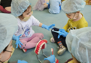 Dzieci w maseczkach, rękawiczkach szczotkują zęby