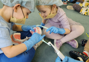 Dzieci w maseczkach, rękawiczkach szczotkują zęby