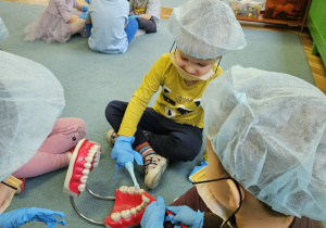 Dzieci w maseczkach, rękawiczkach szczotkują zęby