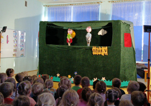 dzieci siedzą w sali oglądając przedstawienie