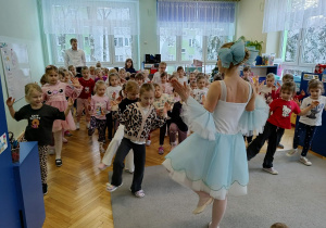 dziewczynki uczą się układu kroków jaki prezentuje baletnica