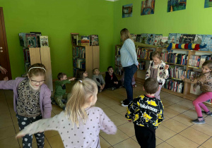 dzieci bawiąc się w kalambury przedstawiają sporty zimowe,