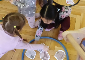 dzieci segregują odpady do kolorowych obręczy