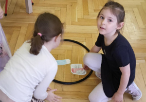 dzieci segregują odpady do kolorowych obręczy