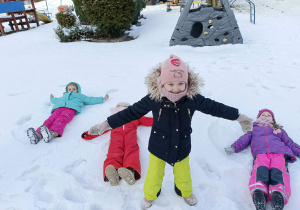 dzieci wykonują "orzełki" na śniegu