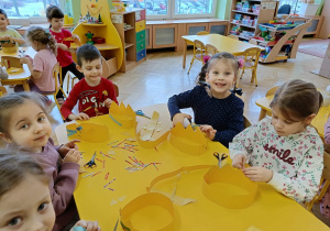 dzieci siedzą przy stolikach, wykonują korony