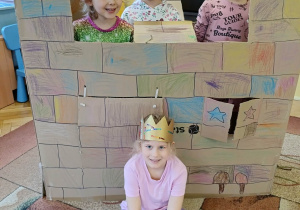 dziewczynki pozują do zdjęcia z kartonowym zamkiem