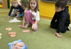 Dzieci rozwiązują zadania matematyczne na dywanie