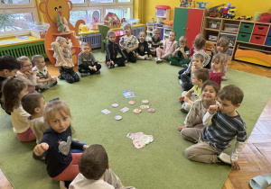 Dzieci rozwiązują zadania matematyczne na dywanie