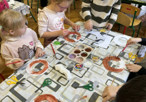 Dzieci przy stolikach wykonują pracę plastyczne