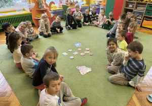 Dzieci rozwiązują zadania matematyczne na dywanie