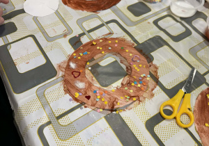 dzieci przy stolikach wykonują pracę plastyczne