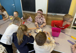 Dzieci przy stolikach wykonują pracę plastyczne