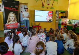 dzieci siedzą na dywanie, słuchają n informacji na temat kampanii