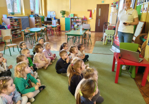 Dzieci z grupy zielonej z zaciekawieniem oglądają prezentacje dotyczącą bezpieczeństwa na przejazdach kolejowych.