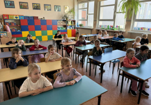 Dzieci siedzą w ławkach