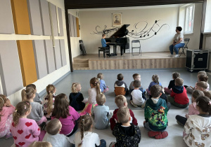 dzieci słuchają koncertu granego na fortepianie przez Tomka,