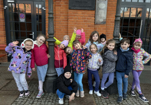 dzieci pozują do zdjęcia przy budynku dawnych zakładów Karola Scheiblera