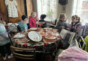 dzieci zwiedzają pomieszczenia mieszkalne w dawnych czasach