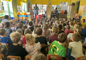 dzieci siedzą w sali i słuchają audycji muzycznej