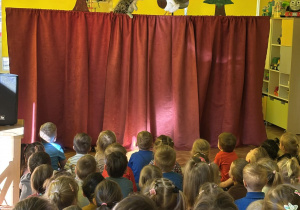 dzieci siedzą w sali, oglądają przedstawienie