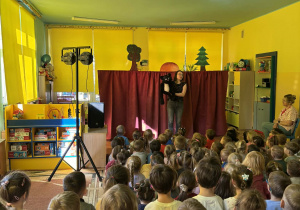 dzieci siedzą w sali, oglądają przedstawienie
