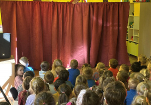 dzieci siedzą w sali, oglądają przedstawienie