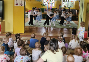 dzieci z grupy czerwonej tańczą, na widowni maluchy oglądają występ