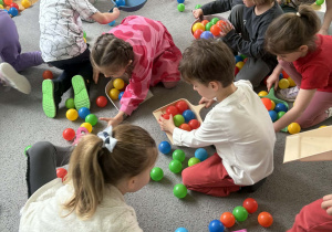 Dzieci sprzątają szufelkami kurz,którym były kolorowe kulki